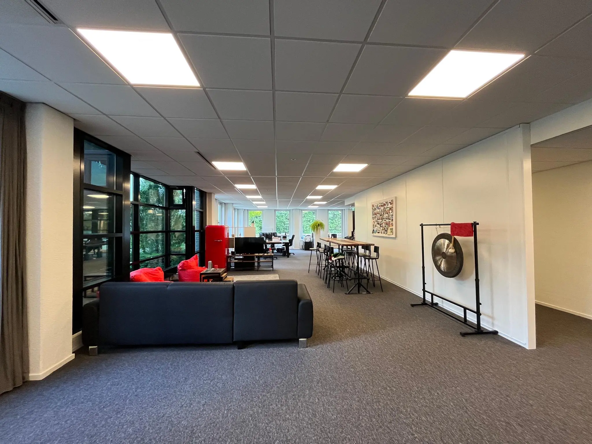 Moderne kantoorruimte aan de Oude Utrechtseweg met zithoek, lange vergadertafel en een grote gong aan de muur.